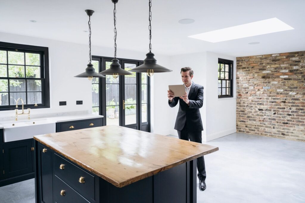Male estate agent using digital tablet to photograph kitchen