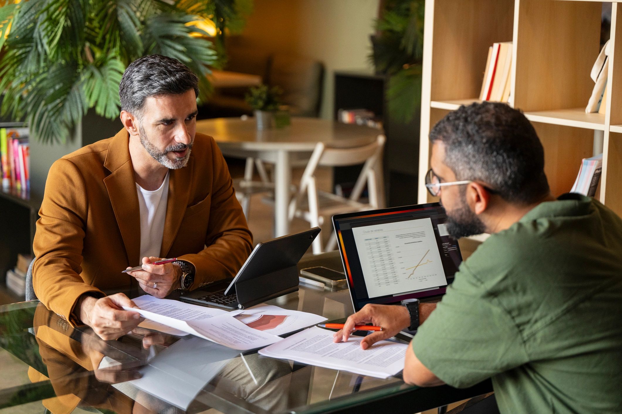 Two professionals reviewing documents and plans during a property management meeting